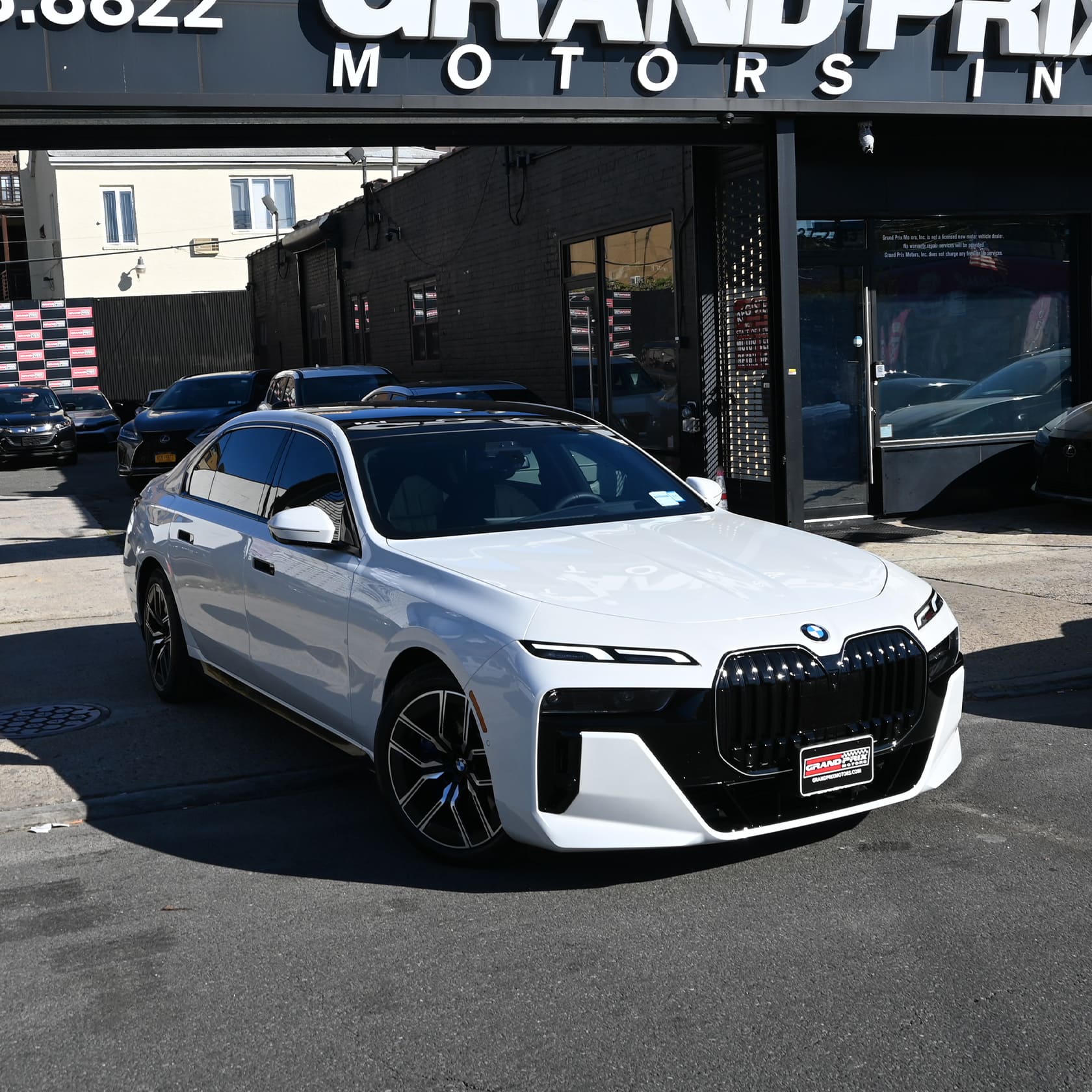 White 2026 BMW 7 Series parked at the Grand Prix Motors lot in Brooklyn